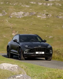 Aston Martin DBX-inspired Apple Watch face featuring a black SUV on a scenic countryside road
