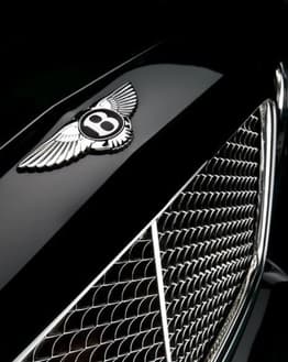 Close-up of the Bentley winged "B" emblem and intricate chrome grille on a sleek black background