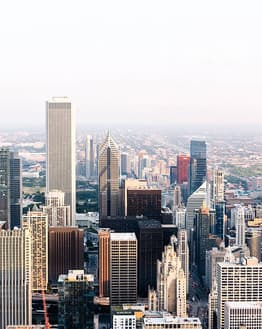 Aerial view of Chicago skyline showcasing skyscrapers and a sprawling urban landscape under a bright sky, displayed on a watch face