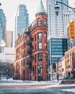 Toronto’s Flatiron Building (Gooderham Building) with its red brick facade, surrounded by modern skyscrapers in a wintry urban setting, displayed on a watch face
