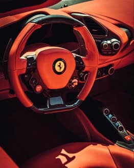 Close-up of a Ferrari steering wheel with premium red leather and detailed controls, featured on a watch face.