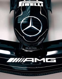 A watch face featuring the Mercedes-Benz logo and AMG branding on a sleek black Formula 1 car design.