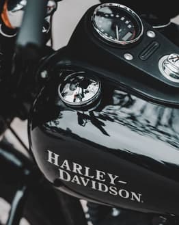 Close-up of a glossy Harley-Davidson fuel tank with the iconic logo and detailed dials, displayed on a watch face.