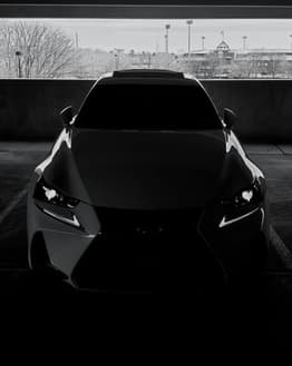 Front view of a luxury car in a blacked-out monochromatic style with sharp headlights, featured on a watch face.