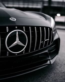 Close-up of the Mercedes-Benz emblem on the AMG grille, featured on a luxury watch face.