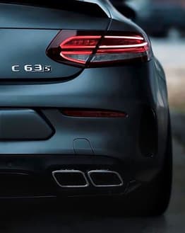 Rear view of the Mercedes-Benz C63 S AMG showcasing taillights and quad exhaust, featured on a watch face.