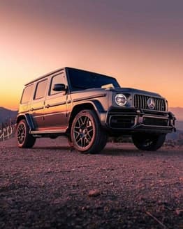 Mercedes-Benz G-Wagon parked on a scenic mountain road during sunset, featured on a luxury watch face.