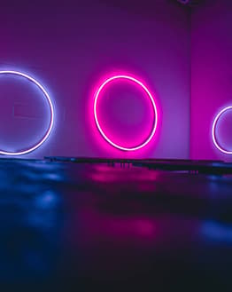 Glowing pink and purple neon circles on a dark futuristic background, featured on a watch face.