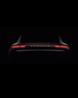 Minimalist rear view of a Porsche with illuminated LED taillights on a dark background, featured on a watch face.