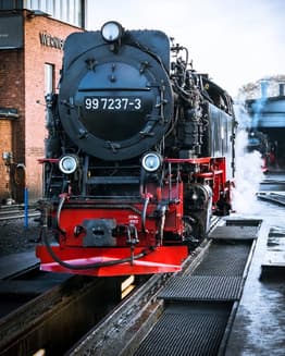 A vintage black and red steam locomotive with number 99 7237-3 at a railway station, designed as a classic watch face