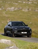 Aston Martin DBX-inspired Apple Watch face featuring a black SUV on a scenic countryside road