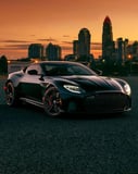 Aston Martin DBS-inspired Apple Watch face featuring a black coupe with red wheels in a sunset cityscape