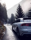 Audi Q8-inspired Apple Watch face featuring a sleek rear view with bold taillights in an alpine forest