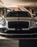 Front view of the Bentley Flying Spur with a sleek silver grille and bold headlights, featured on a watch face