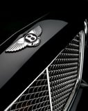 Close-up of the Bentley winged "B" emblem and intricate chrome grille on a sleek black background