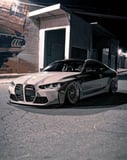 BMW M4 coupe parked on a city street at night with a mural in the background, featured on a watch face