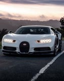 Front view of a white Bugatti Chiron on a scenic road at dusk, featured on a watch face.
