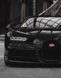 Front view of a black Bugatti Chiron in an elegant indoor setting, featured on a watch face.