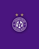 The Austria Wien crest featuring purple and white details, the club initials (FAK), and two golden stars, set against a deep purple background, featured on a watch face.