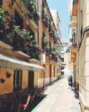 Sunlit Mediterranean alley with vibrant flowers on balconies and cozy outdoor cafes, displayed on a watch face