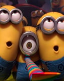 Three Minions dressed in blue overalls, blowing a rainbow party horn, with excited expressions and festive vibes, featured on a watch face.