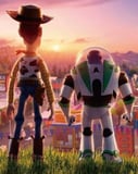 Illustration of Woody and Buzz Lightyear standing together, watching a sunset over a carnival, featured on a watch face.