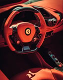 Close-up of a Ferrari steering wheel with premium red leather and detailed controls, featured on a watch face.