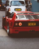 Rear view of a red Ferrari F40 driving through city streets, showcasing its iconic taillights and bold design, featured on a watch face.