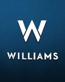 A watch face featuring the Williams Racing "W" logo on a dark blue background.