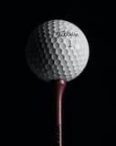 A watch face featuring a close-up of a Titleist golf ball on a tee with a dark background.