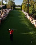 Golfer mid-swing on a championship golf course surrounded by spectators, capturing the energy of professional golf, displayed on a watch face.