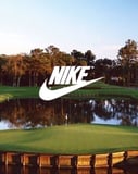 Scenic golf course with a water hazard and the Nike logo, surrounded by trees and open skies, displayed on a watch face.