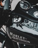 Close-up of a glossy Harley-Davidson fuel tank with the iconic logo and detailed dials, displayed on a watch face.