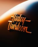 Close-up of the Harley-Davidson emblem with a warm gradient finish, displayed on a watch face.