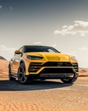 Yellow Lamborghini Urus SUV in a desert setting under a clear sky, showcasing luxury and off-road performance, featured on a watch face.