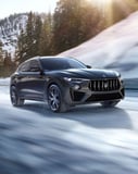 Maserati Levante SUV driving on a snowy mountain road, featured on a luxury watch face.