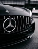 Close-up of the Mercedes-Benz emblem on the AMG grille, featured on a luxury watch face.