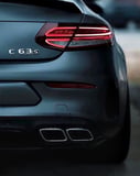 Rear view of the Mercedes-Benz C63 S AMG showcasing taillights and quad exhaust, featured on a watch face.