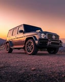 Mercedes-Benz G-Wagon parked on a scenic mountain road during sunset, featured on a luxury watch face.