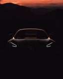 Silhouette of a Mercedes car with glowing headlights, set against a dramatic mountain sunset, featured on a watch face.