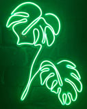 Glowing green neon outline of monstera leaves on a dark background, featured on a watch face.