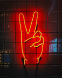 Neon peace sign in yellow on a red tiled background, designed for a watch face.