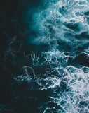 Aerial view of deep blue ocean waves with foamy white surf, designed for a watch face.