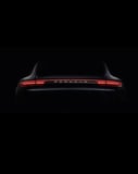 Minimalist rear view of a Porsche with illuminated LED taillights on a dark background, featured on a watch face.