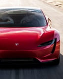 Tesla Roadster Red Edition watch face with the front view of a striking red Tesla Roadster on an open road