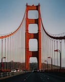 Photograph of the Golden Gate Bridge in San Francisco, showing its red suspension structure and scenic roadway during sunset, featured on a watch face.