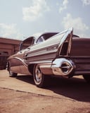 A vintage chrome-finned classic car parked under a sunny sky, designed as a stylish retro watch face